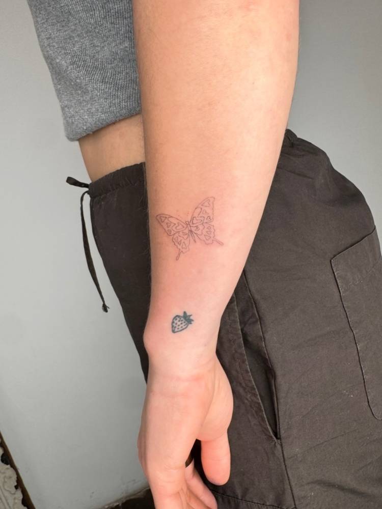 Little butterfly tattooed on the wrist, done in fine line style.