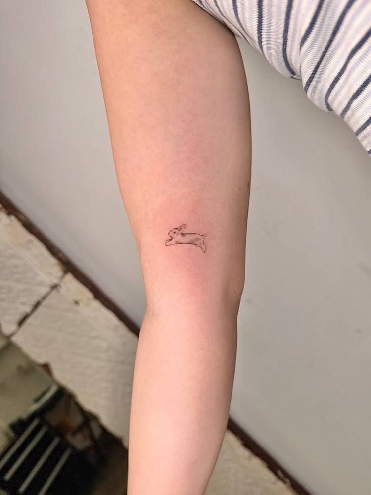 Cute little bunny in illustrative style tattooed on the inner arm.