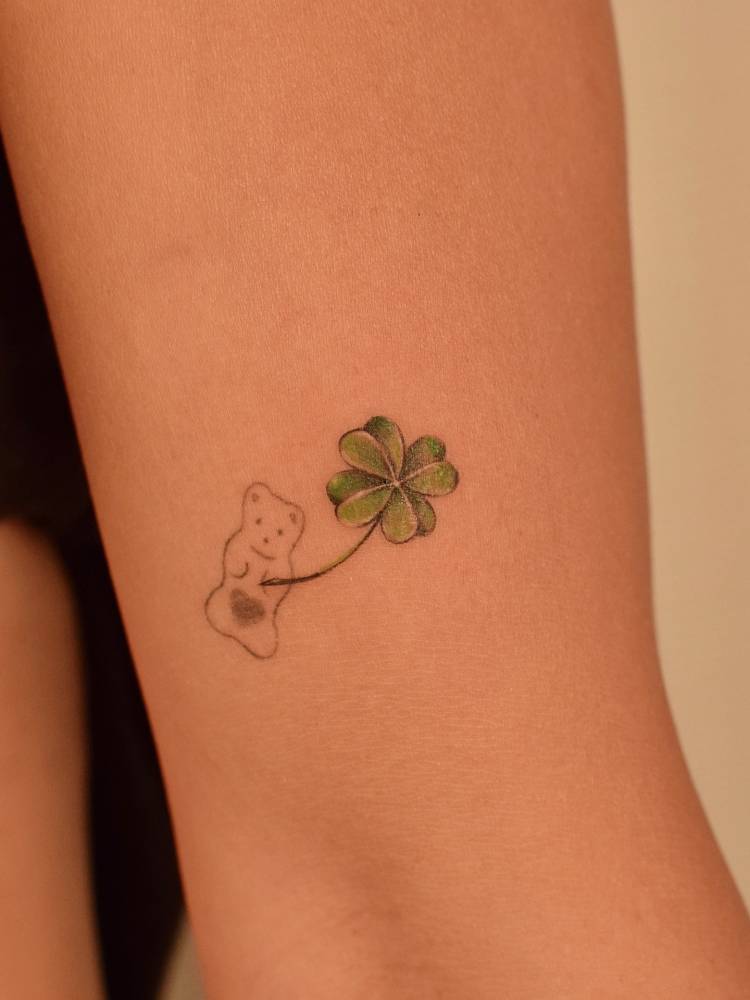 Gummy bear and four leaf clover tattoo located on the upper arm.