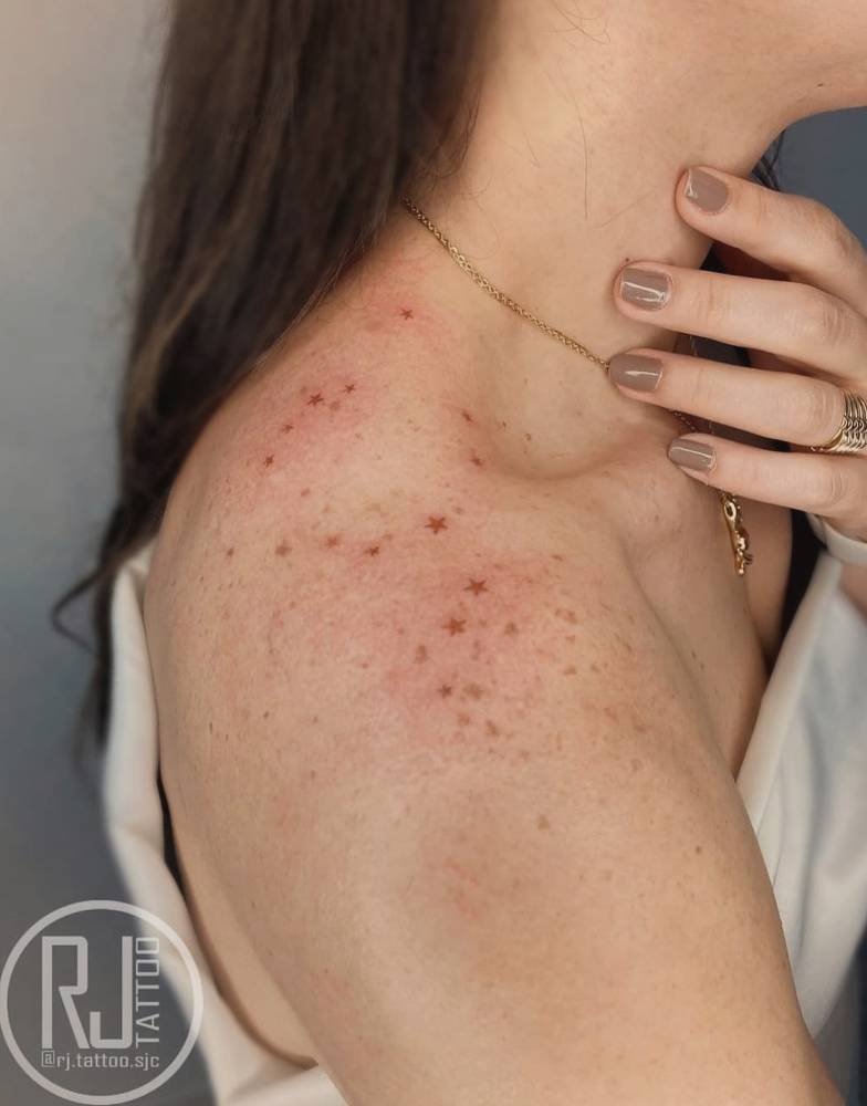 Star freckles tattooed on the top of shoulder.