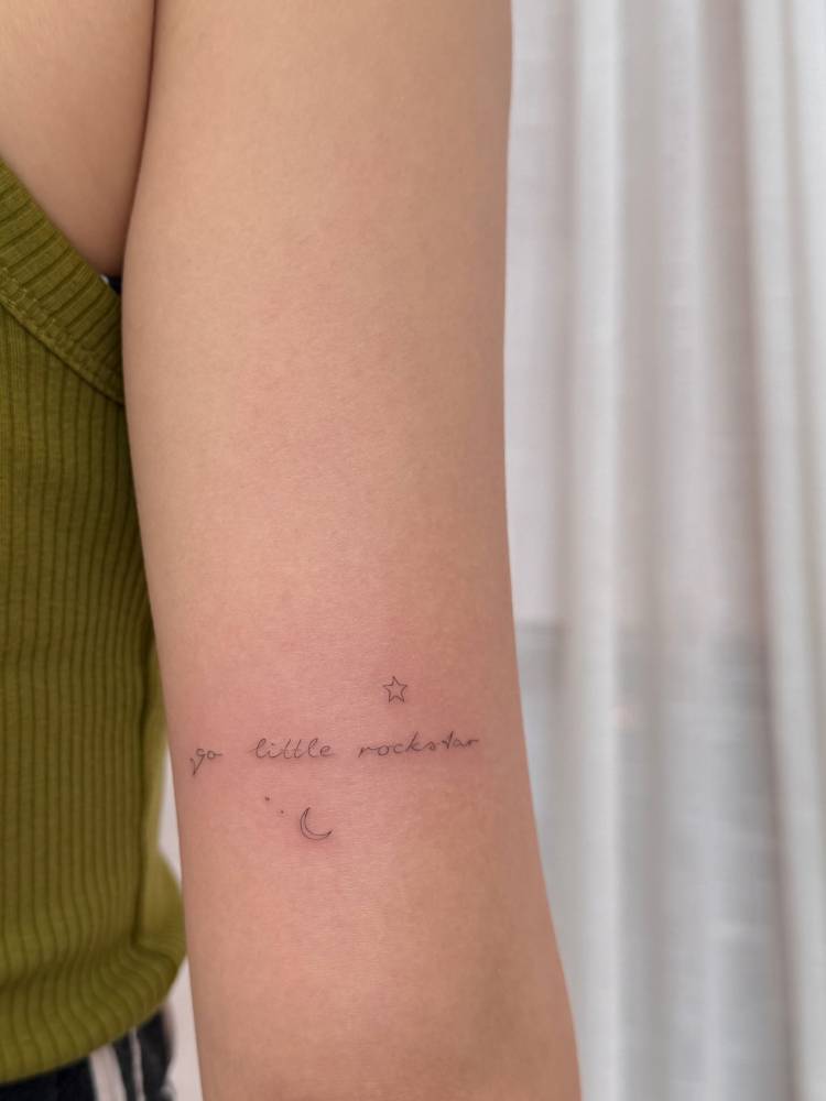 "Go little rockstar" lettering tattoo placed on the tricep.