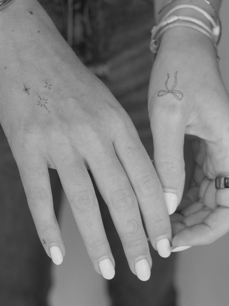 Sparkling stars and bow tattoos located on the hands.