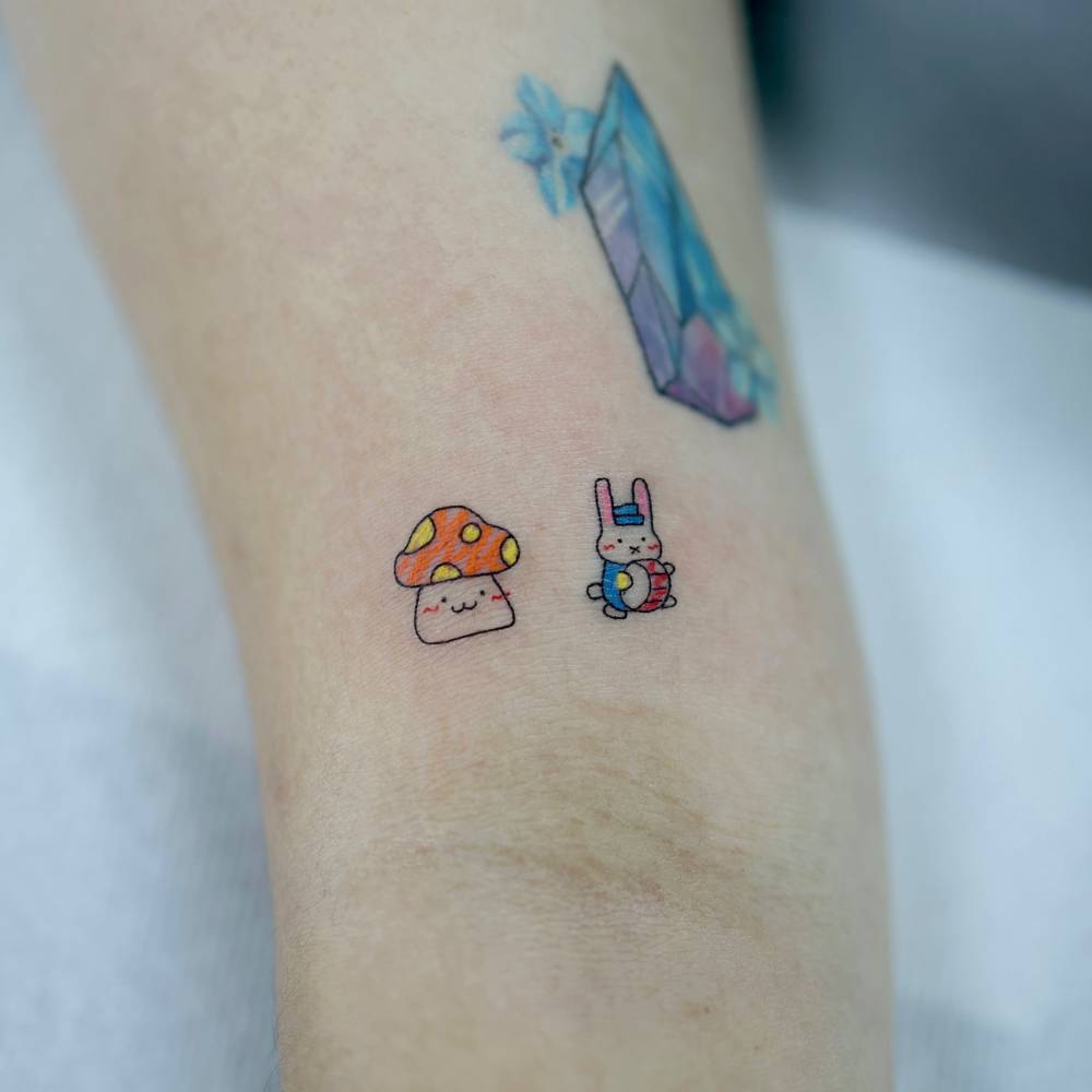 Cartoon style mushroom and rabbit tattoo located on the bicep.