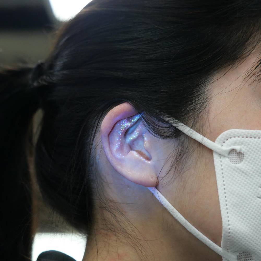 Glitter effect UV ink tattoo located on the ear.