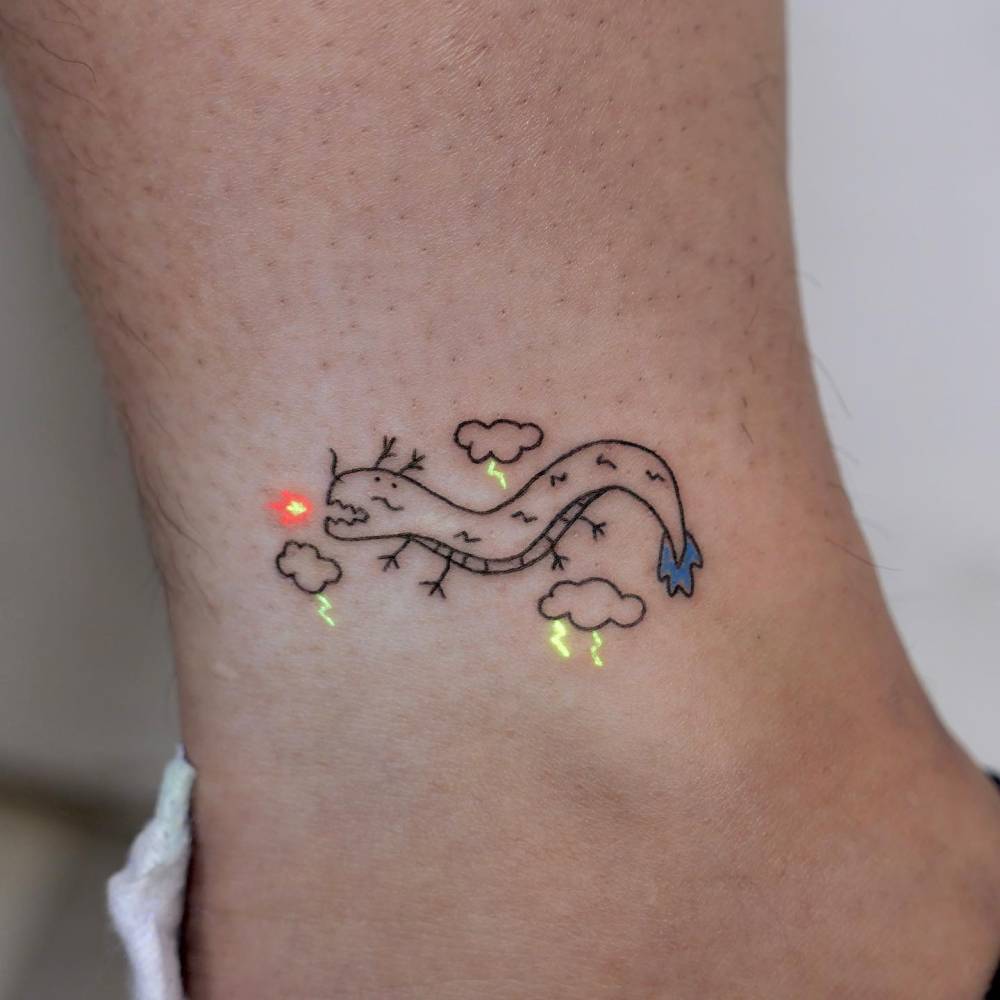 UV ink dragon tattoo in cartoon style located on the ankle.