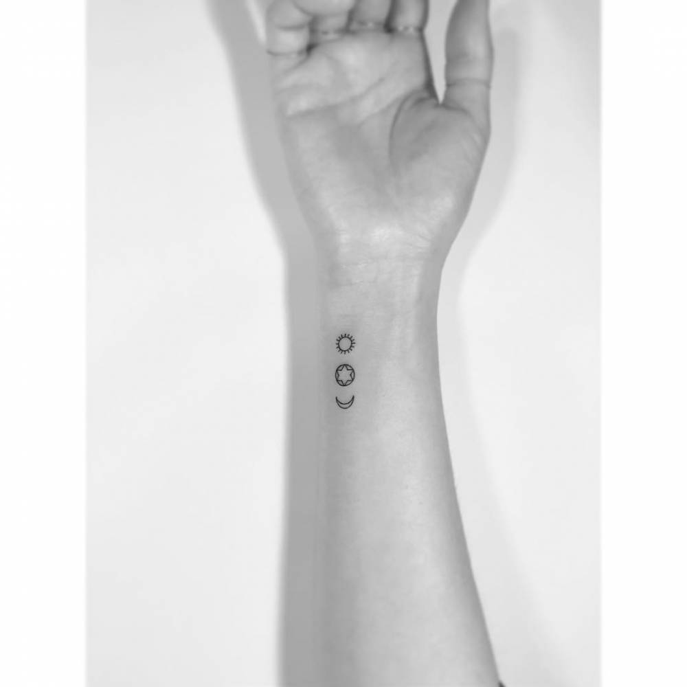 Sun, moon and star tattoo in minimalistic style placed on the wrist.
