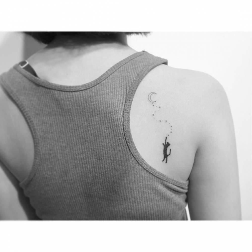 Cat and moon tattoo in minimalistic style located on the shoulder blade.