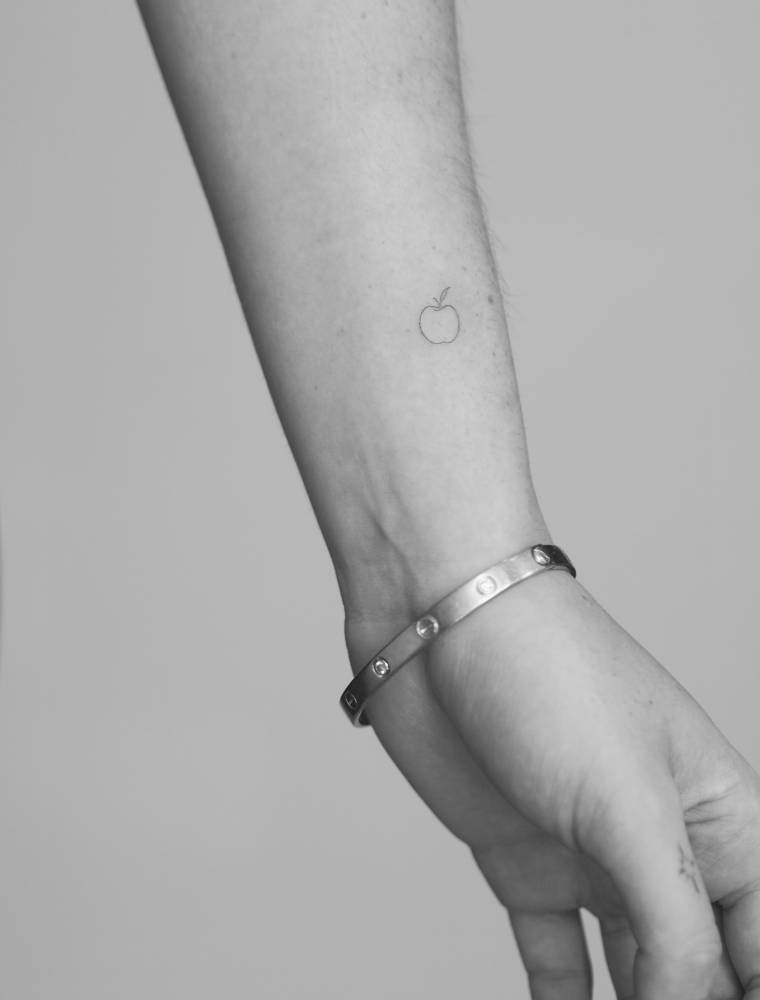 Tiny minimalistic apple tattoo in fine line style.