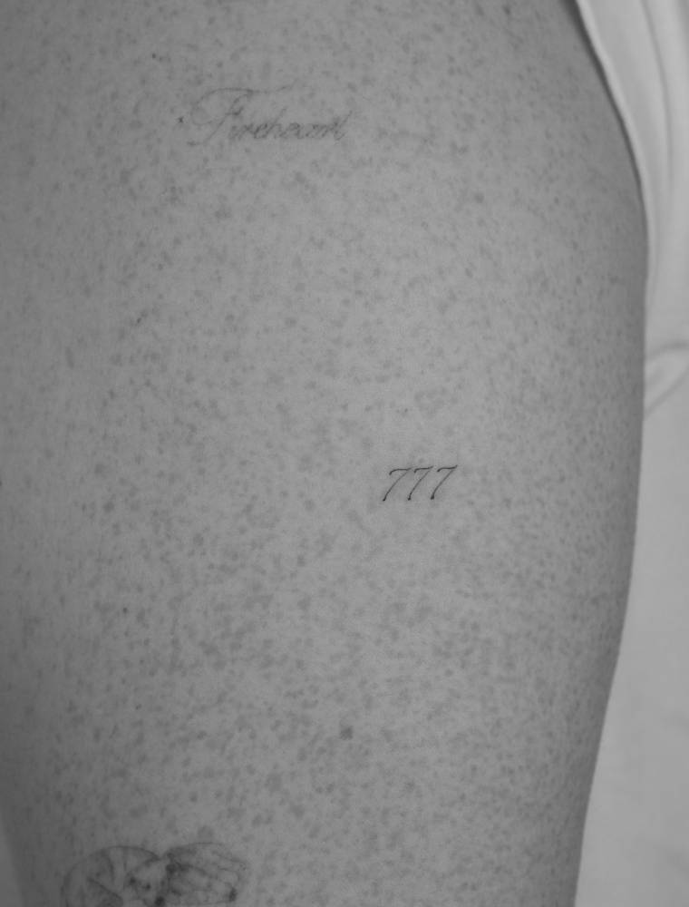 Angel number "777" tattoo located on the upper arm.