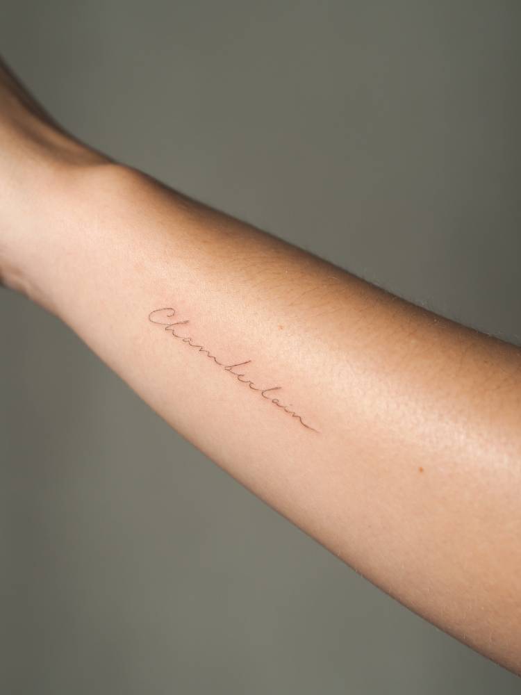 "Chamberlain" lettering tattoo handwritten on the wrist.
