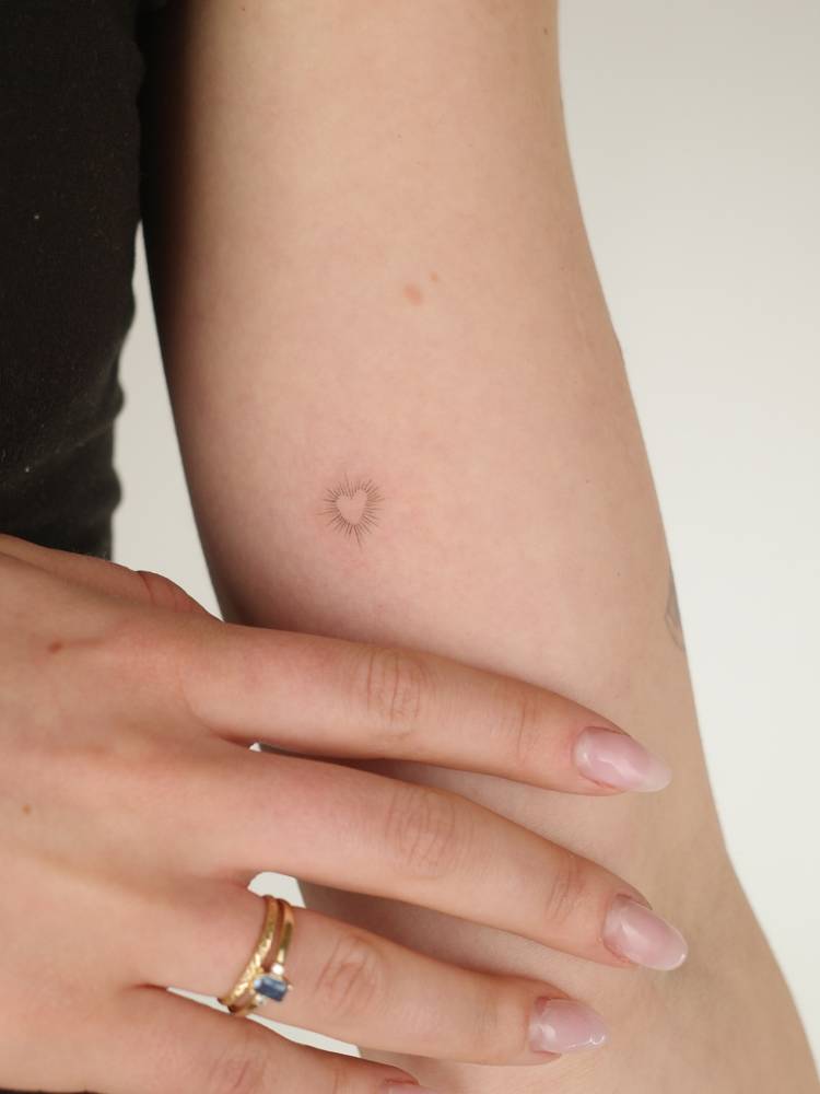 Little shiny heart tattoo located on the inner arm.