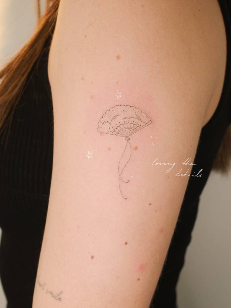 Fine line style hand fan tattoo located on the upper arm.