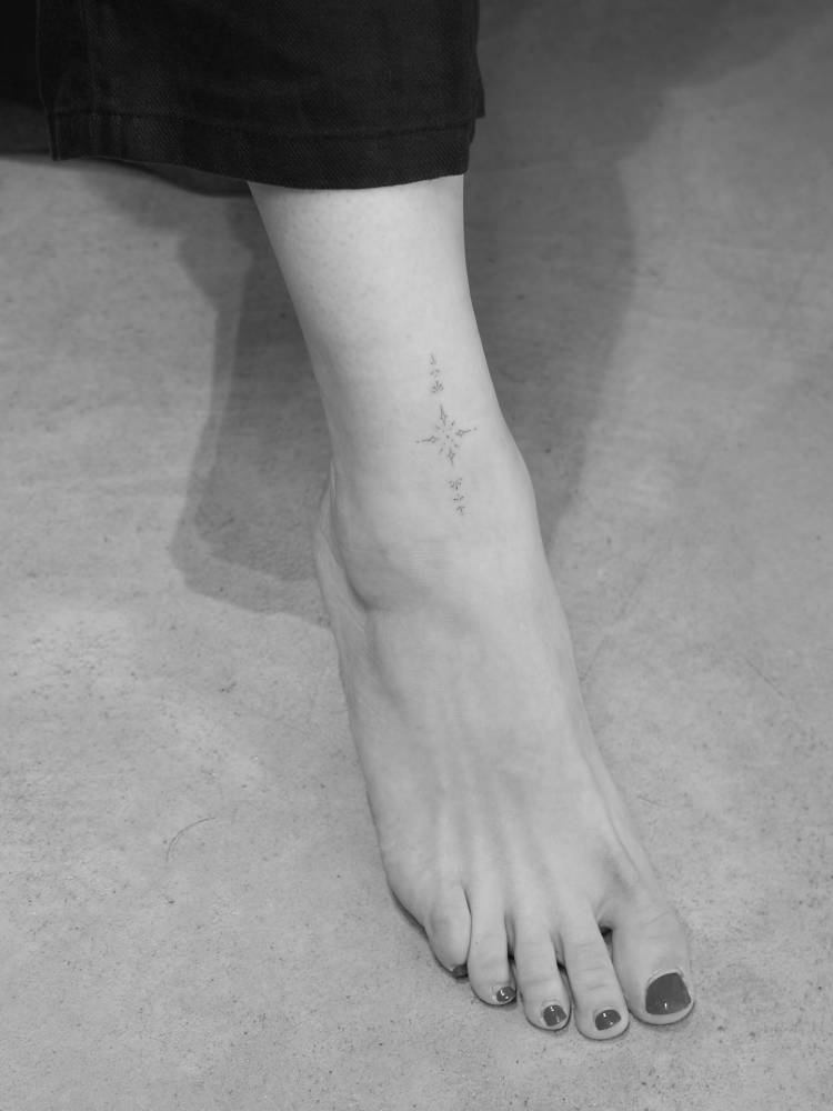 Ornamental tattoo in fine line style located on the ankle.