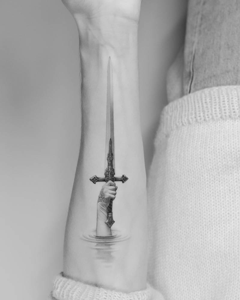 Micro-realistic style sword tattoo located on the inner forearm.
