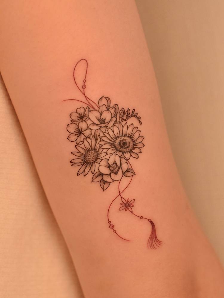 Flower bouquet norigae tattoo located on the tricep.