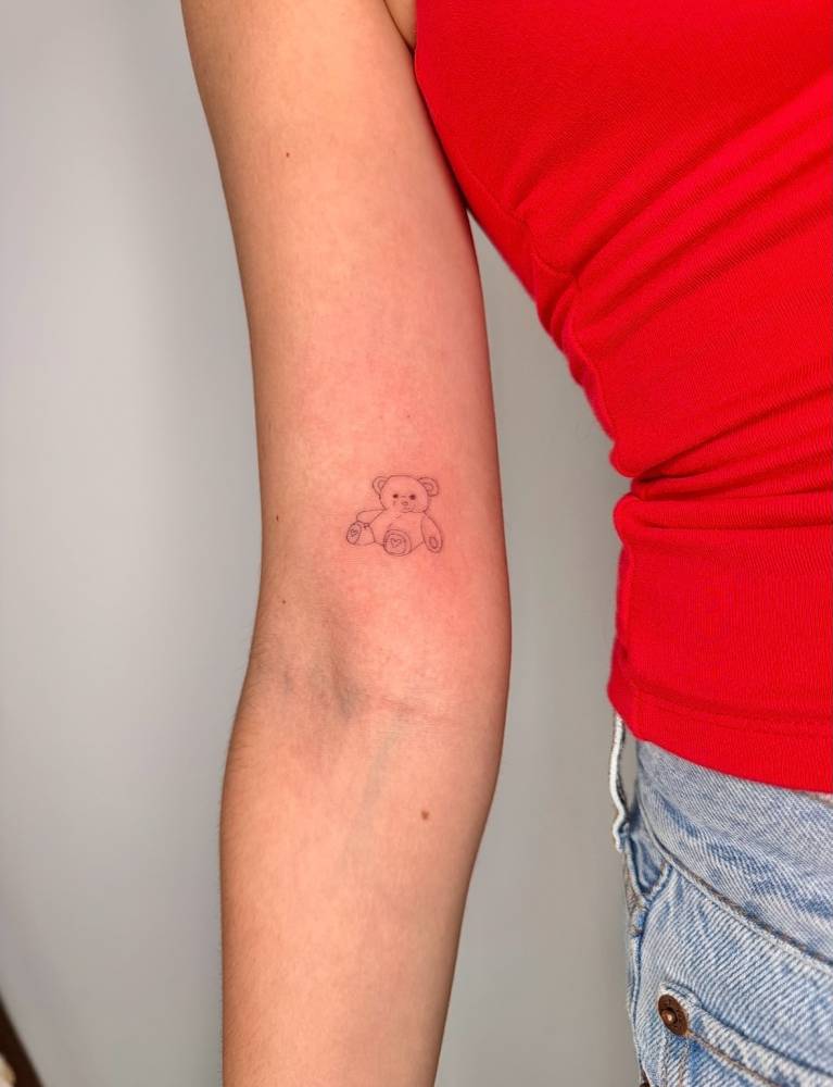 Cute teddy bear in fine line style tattooed on the inner arm.