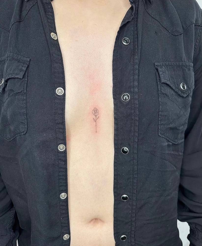 Rose tattoo located on the sternum, done in fine line style.