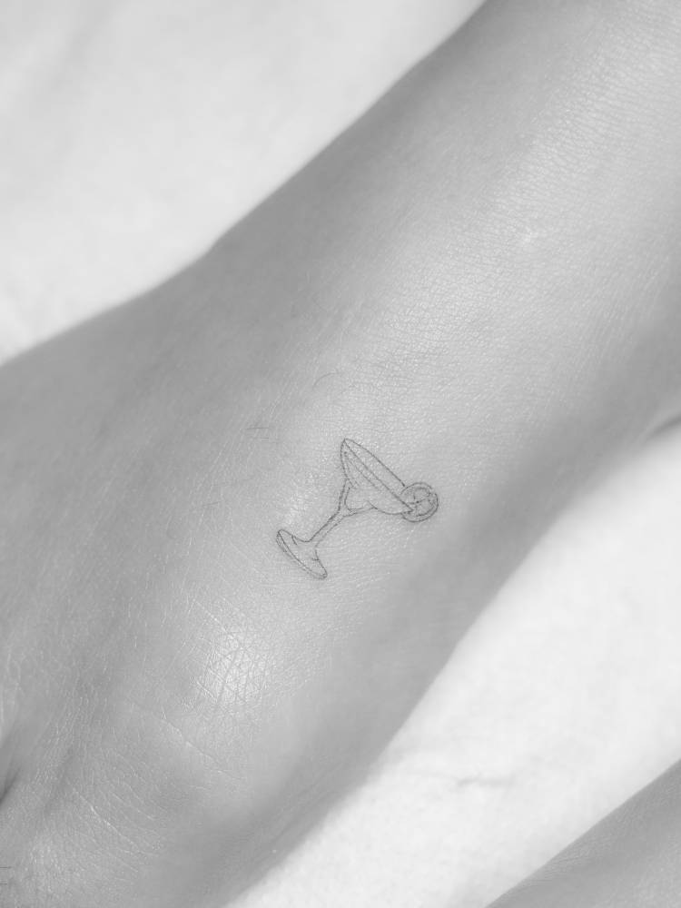 Margarita cocktail tattoo located on the foot, done in fine line style.