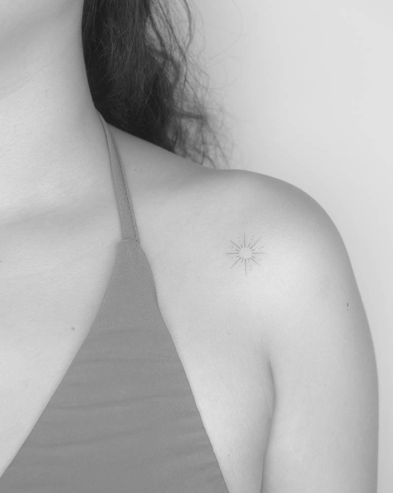 Little sun tattoo in minimalistic style located on the shoulder.