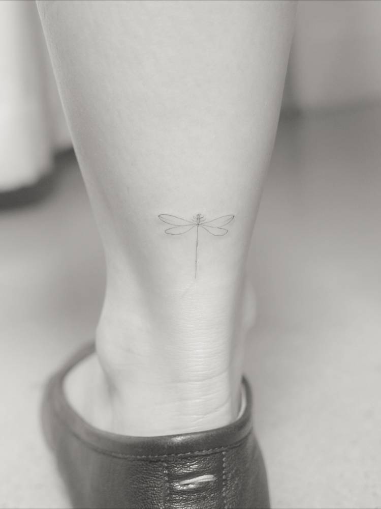 Fine line style dragonfly tattoo done on the achilles.