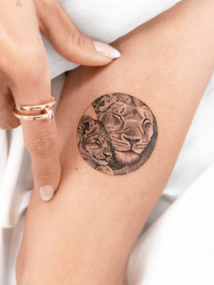 Lioness and cub portrait tattoo located on the inner arm.