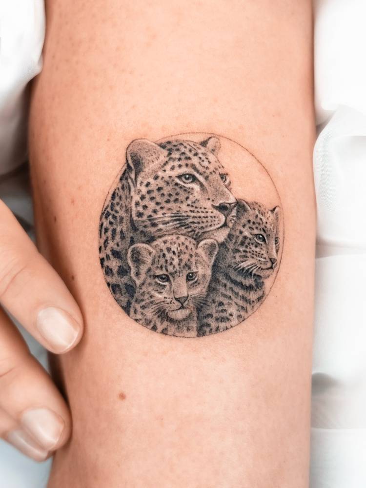 Leopard family tattoo located on the tricep, micro-realistic style.