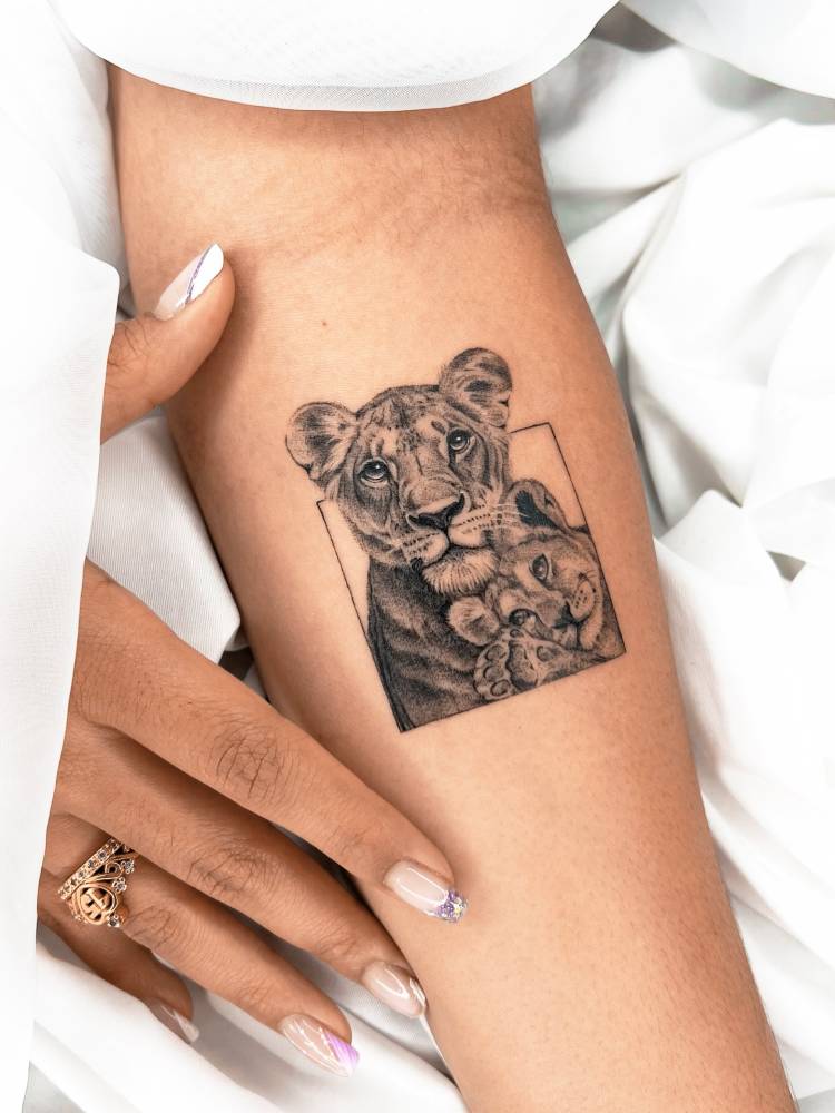 Micro-realistic style lioness and cub tattoo located on the inner forearm.