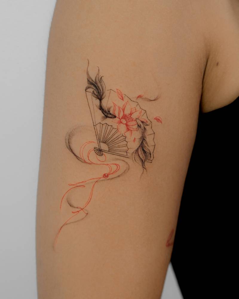 Two opposite fish and hand fan tattoo located on the upper arm.
