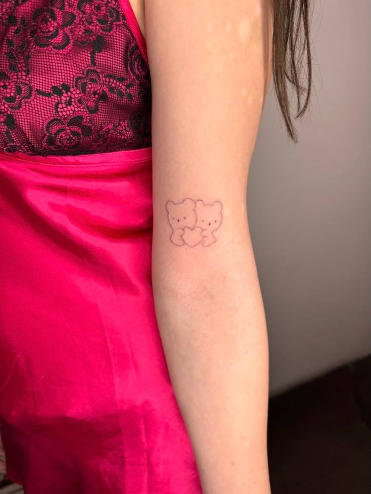 Cute bears tattoo in fine line style located on the bicep.