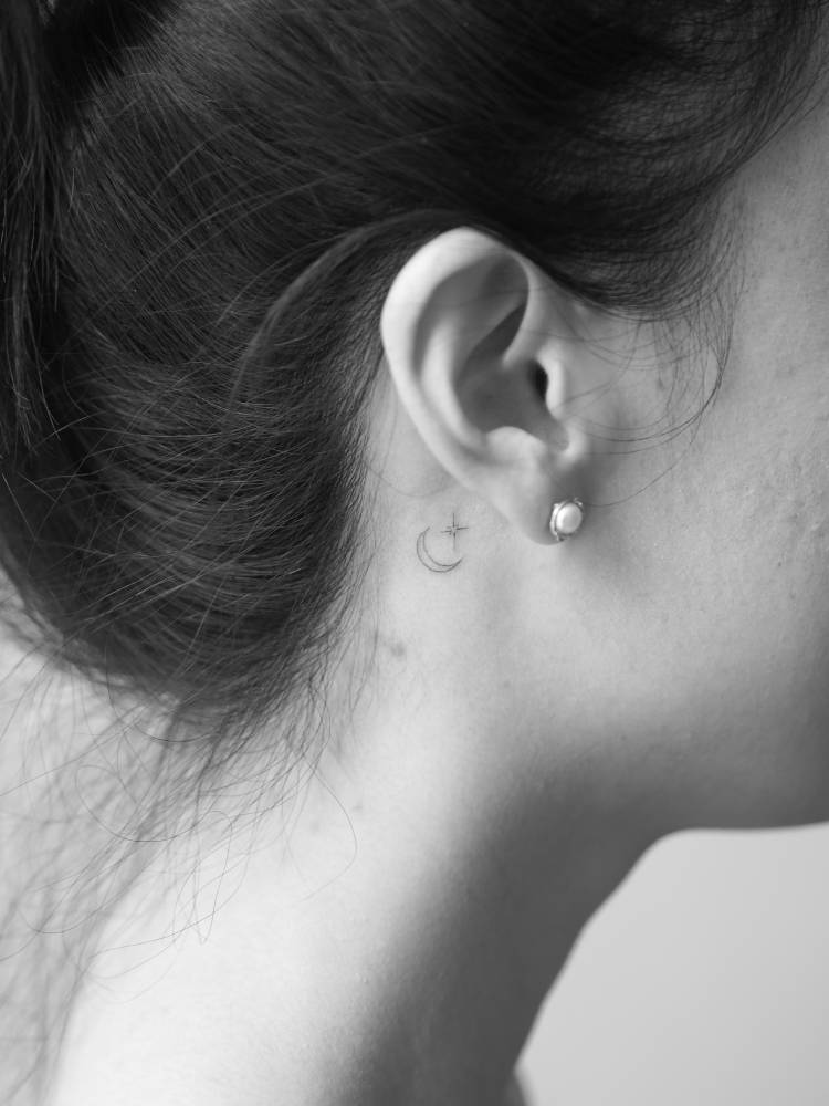Crescent moon and north star tattoo located behind the ear.