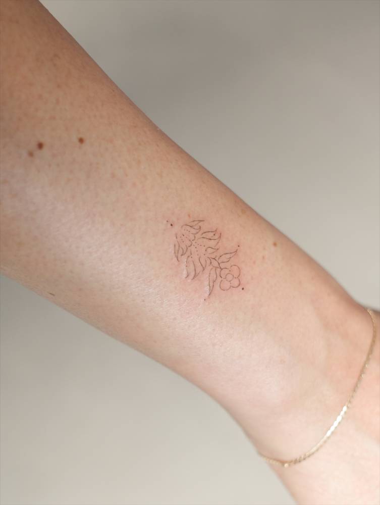 Ornamental flower in fine line style tattooed on the wrist.