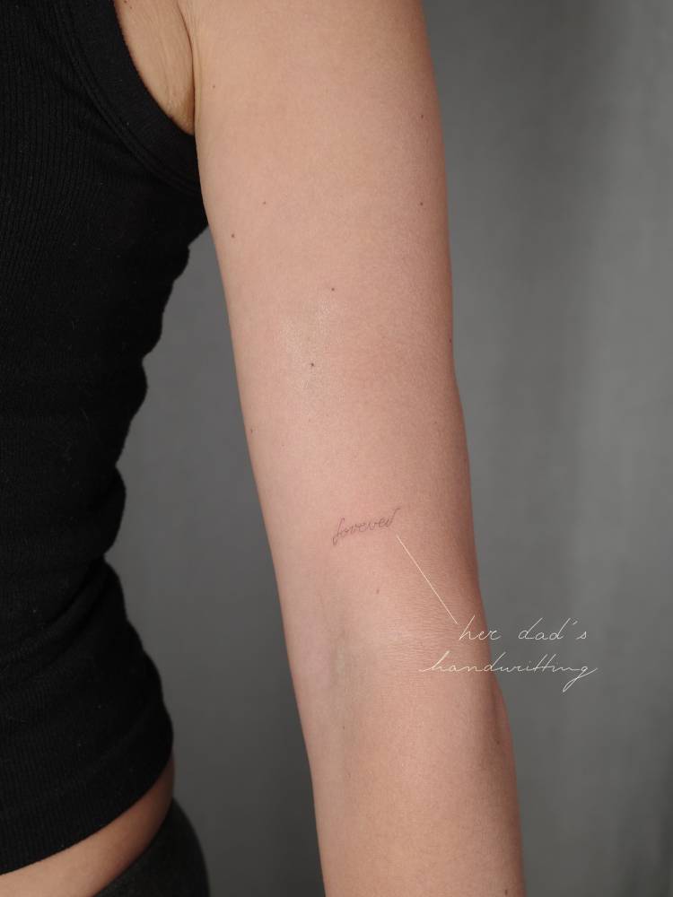 Word "forever" in her dad's handwriting tattooed on the upper arm.