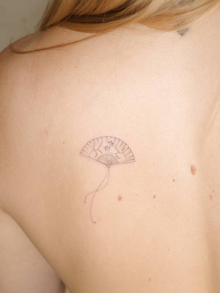 Hand fan tattoo done on the shoulder blade, fine line style.
