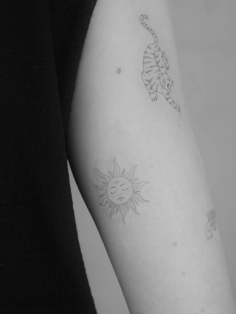 Inti tattoo located on the inner arm, done in fine line style.