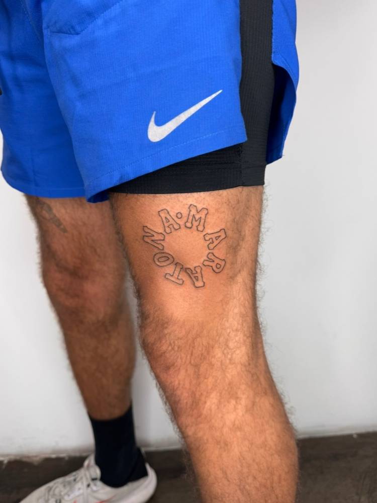 Lettering tattoo of the word "maratona" located on the thigh.
