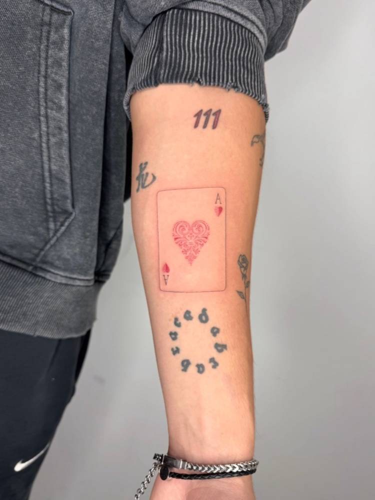 Ace of Hearts tattoo in red ink located on the inner forearm.