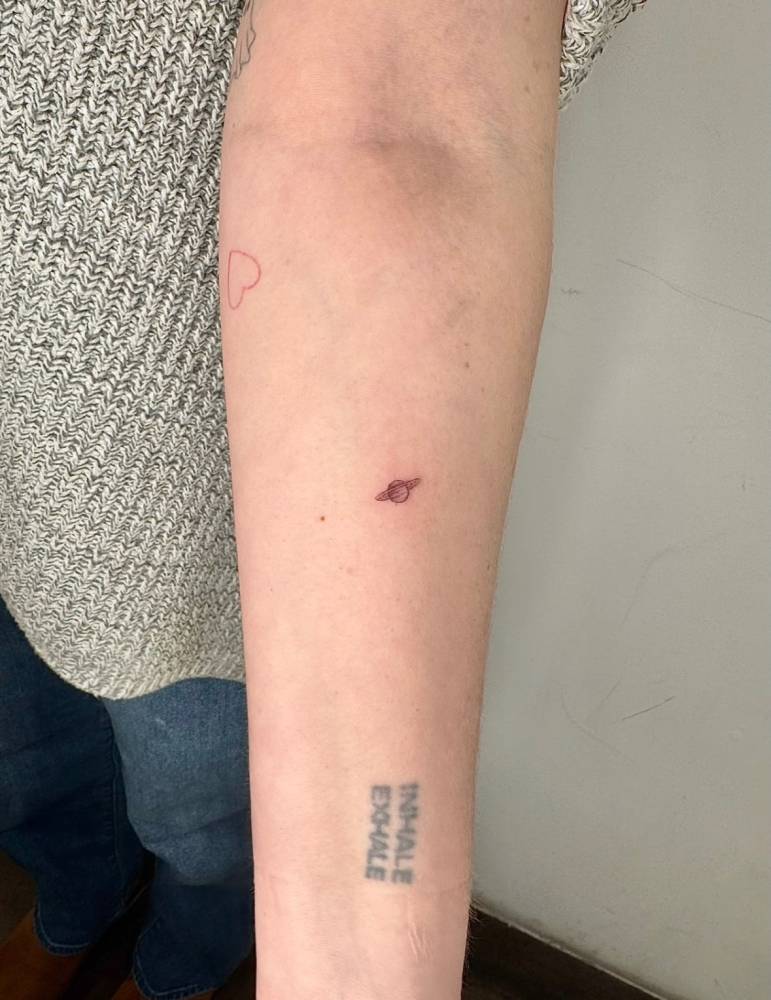Tiny minimalistic Saturn tattoo located on the inner forearm.