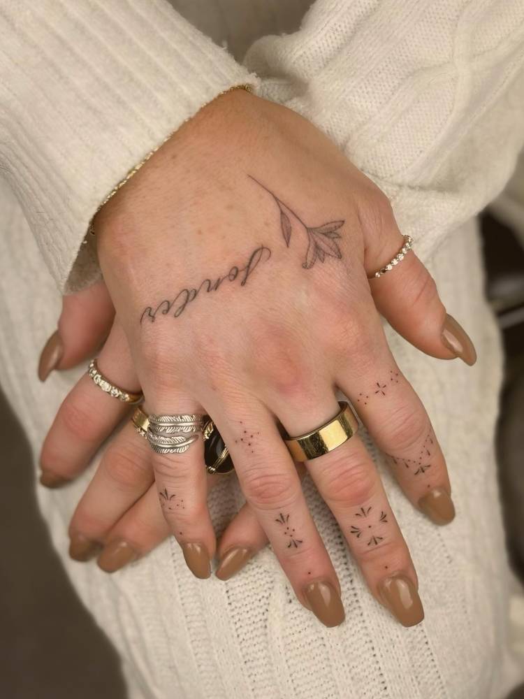 Word "sonder" and flower tattoo located on the hand.