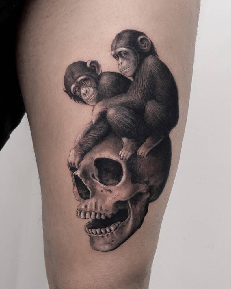 Chimps and skull tattoo in black and grey style located on the thigh.