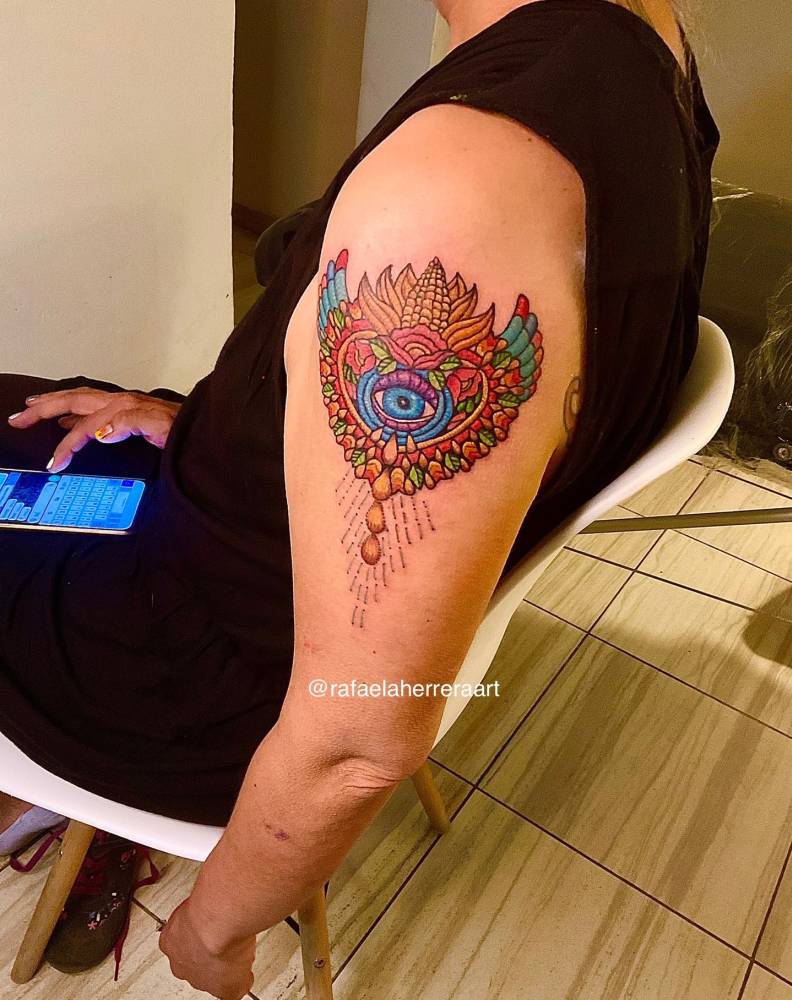 Mexican embroidery evil eye tattoo located on the upper forearm.
