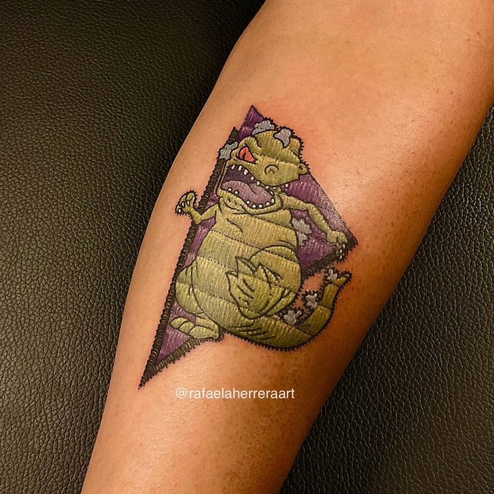 Reptar tattoo in embroidery style located on the inner forearm.