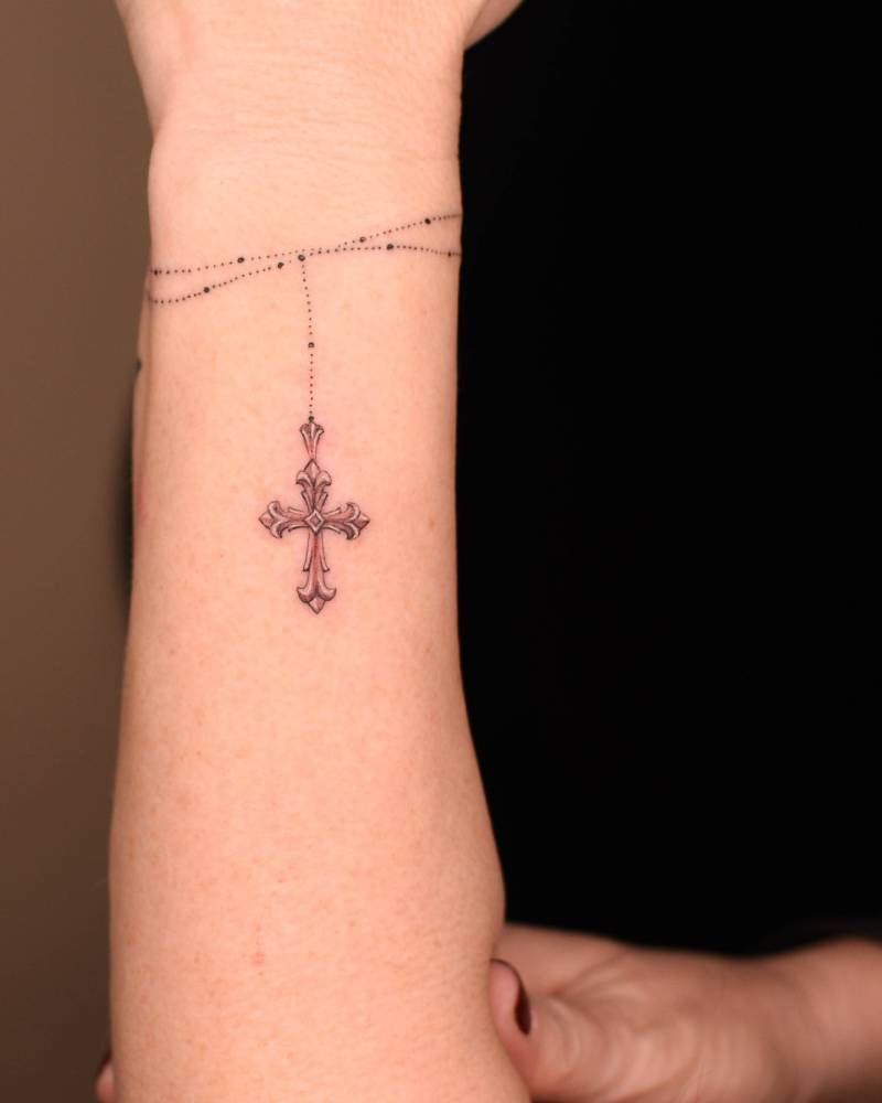 Rosary tattoo located on wrist, illustrative style.