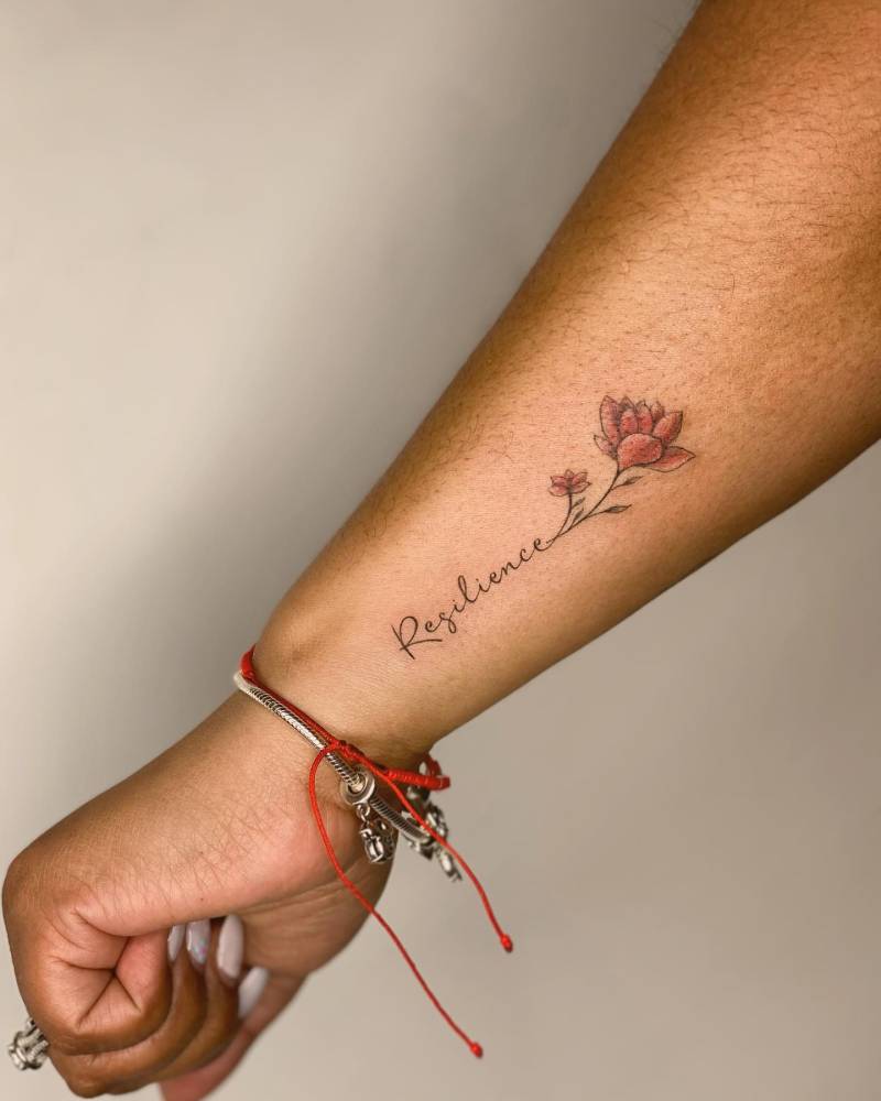 Lotus flower and word "resilience" tattoo located on the wrist.