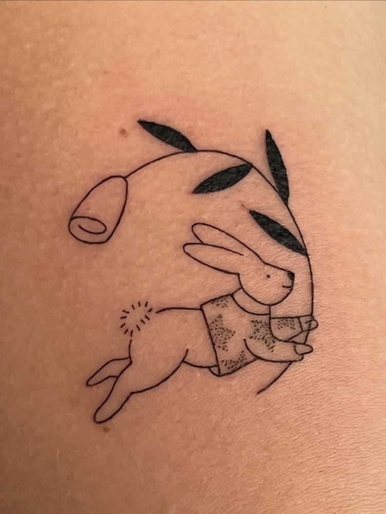 Bunny holding a flower tattooed on the inner forearm.