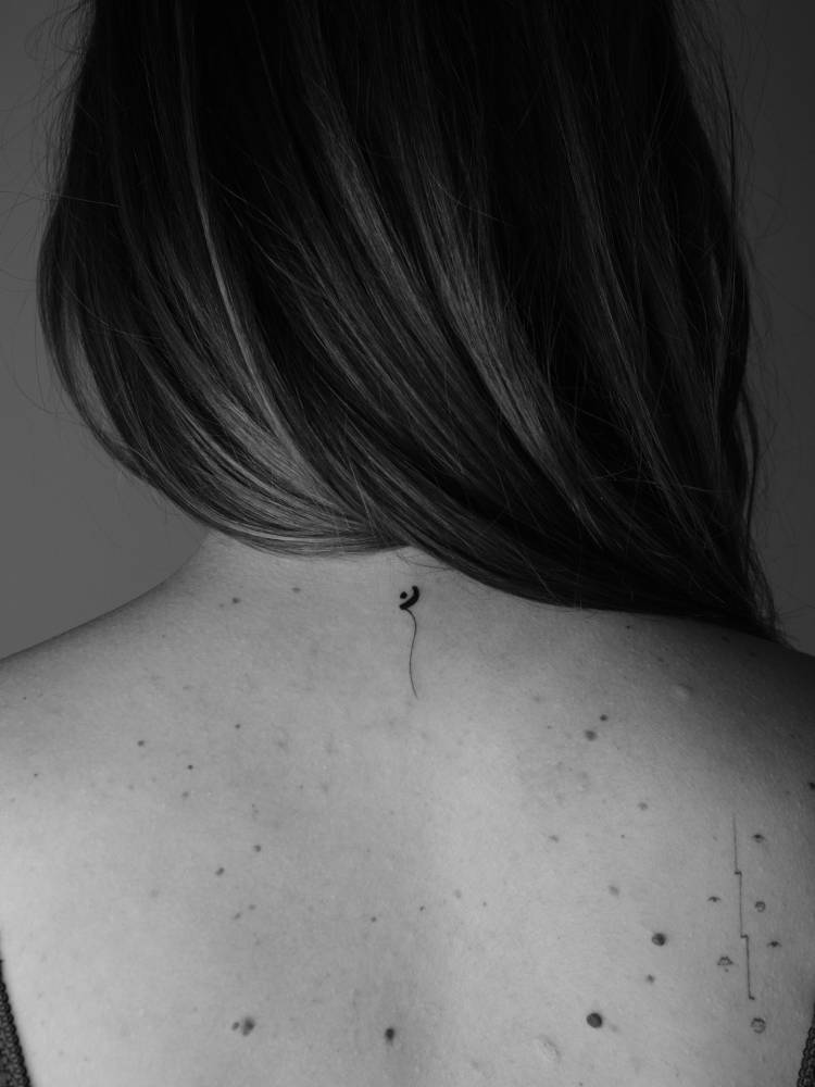 Little abstract design tattooed on the upper back.