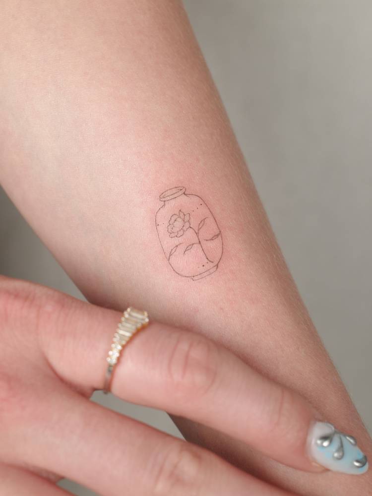 Flower in a bottle tattoo in fine line style.