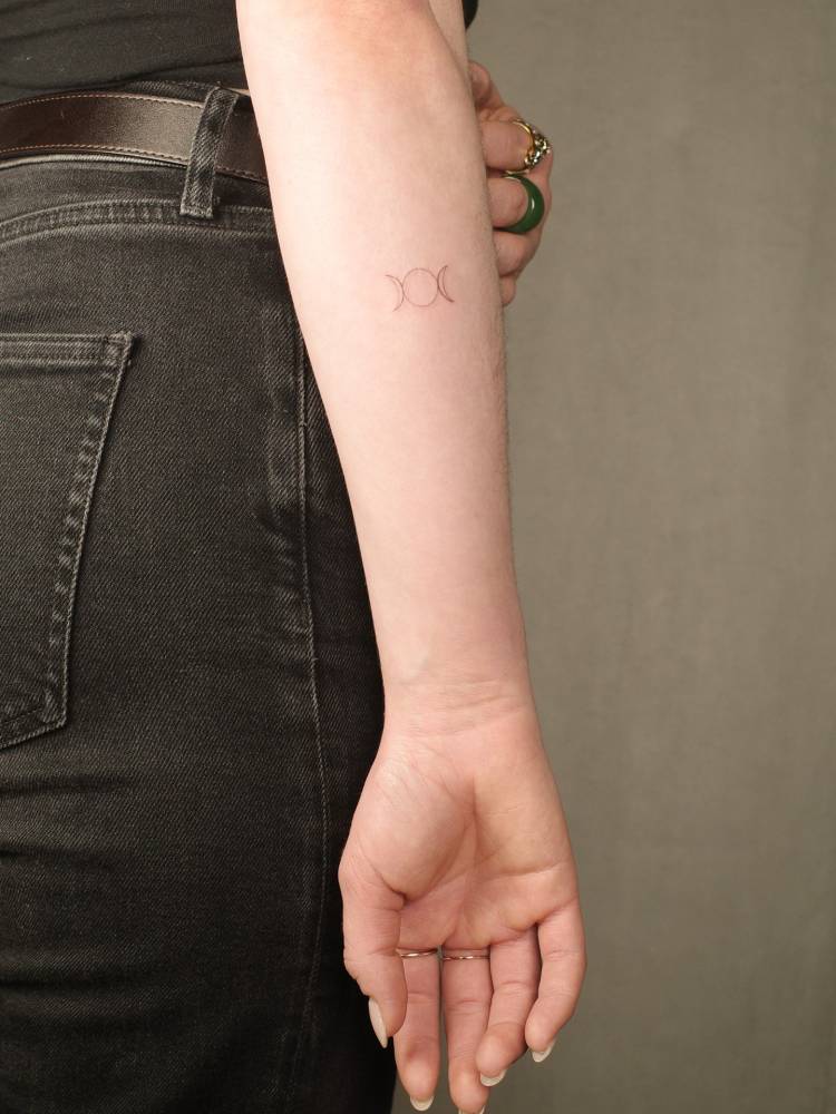 Tiny minimalist triple moon tattoo located on the inner forearm.