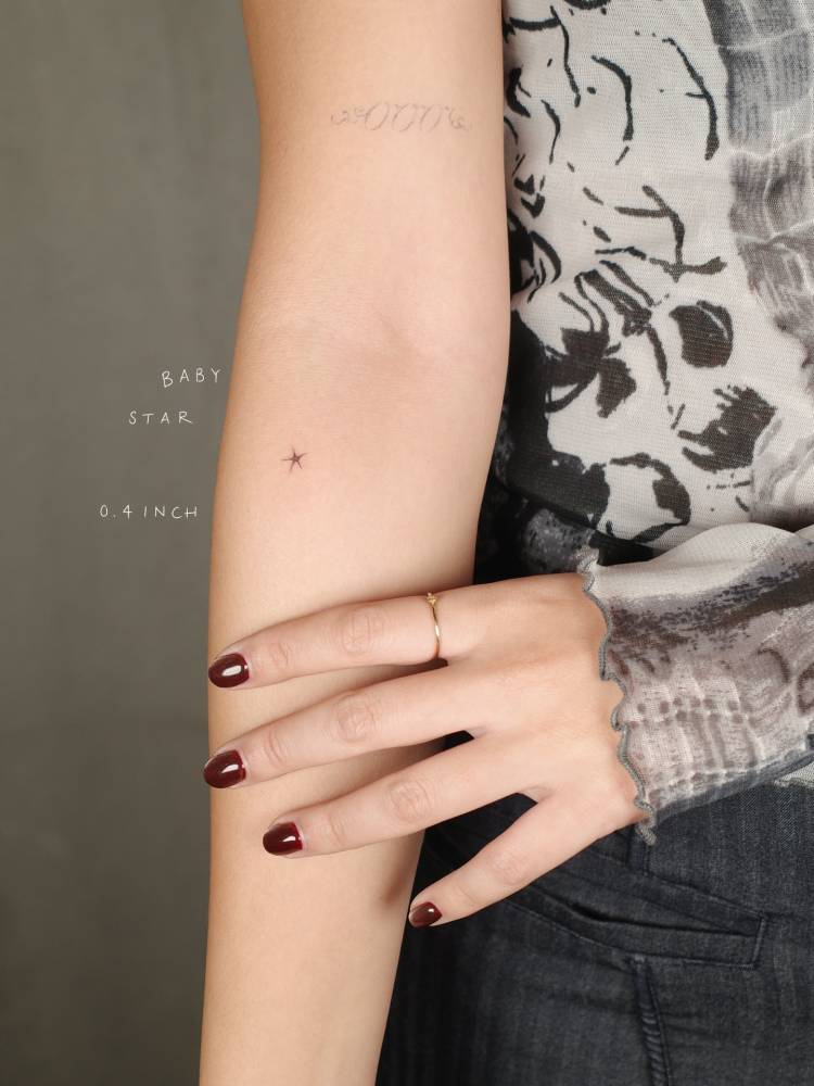 Micro star tattoo located on the inner forearm, minimalistic style.