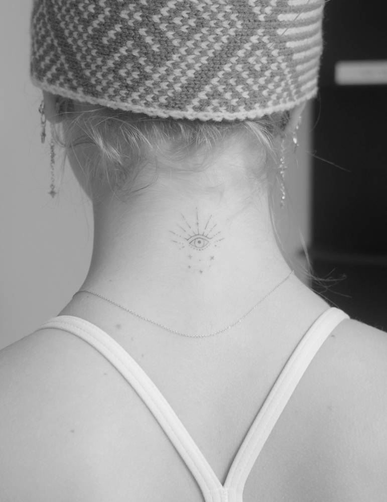 Ornamental evil eye tattoo in fine line style done on the back of the neck.