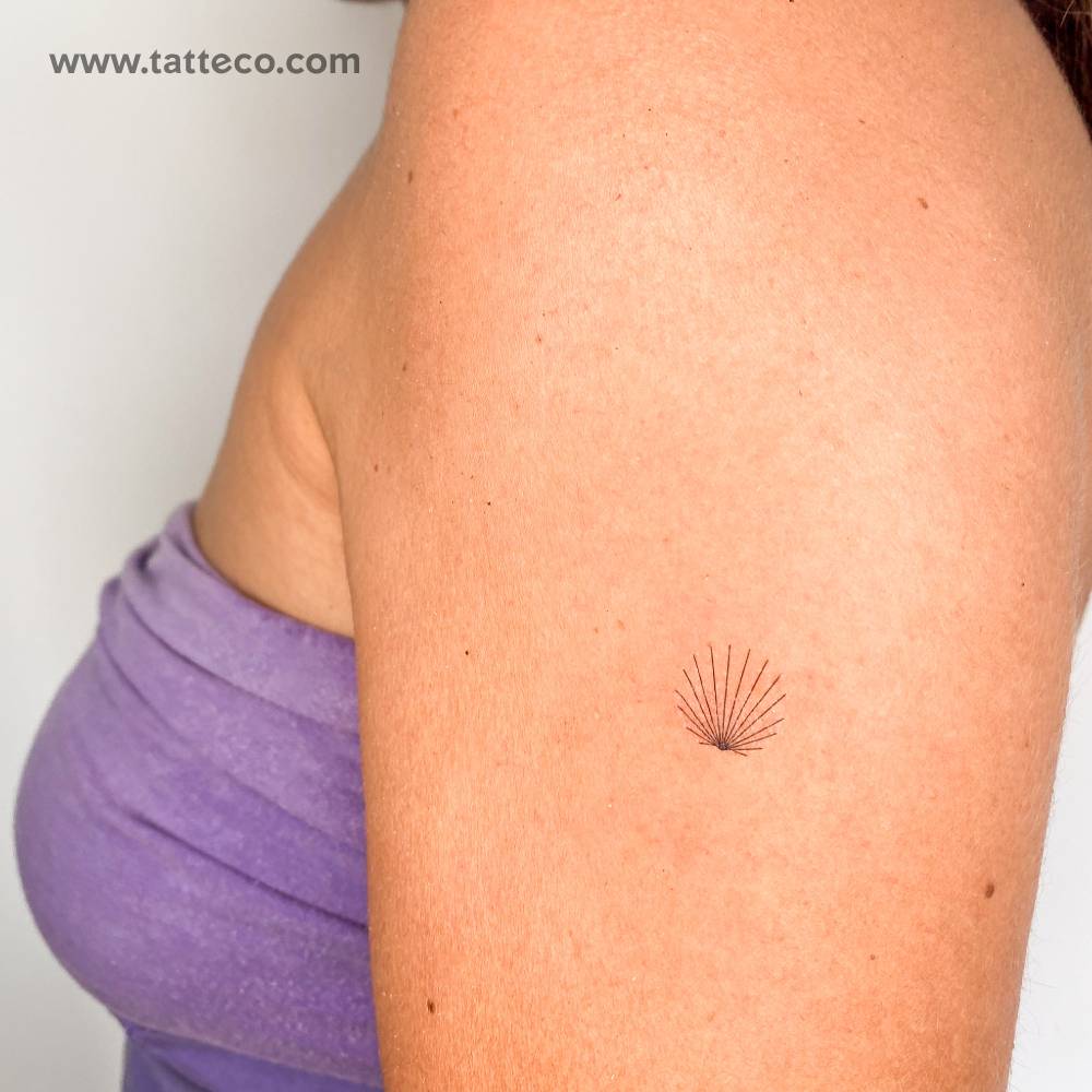 Minimalist shell temporary tattoo located on the upper arm.